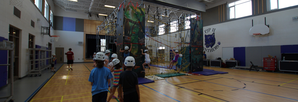 Students in a gym climbing high ropes